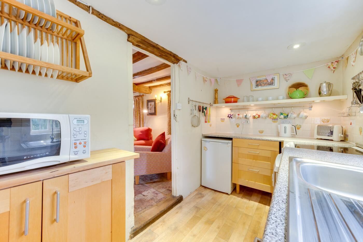 A compact kitchen with a microwave, a small refrigerator, wooden cabinets, and a sink.