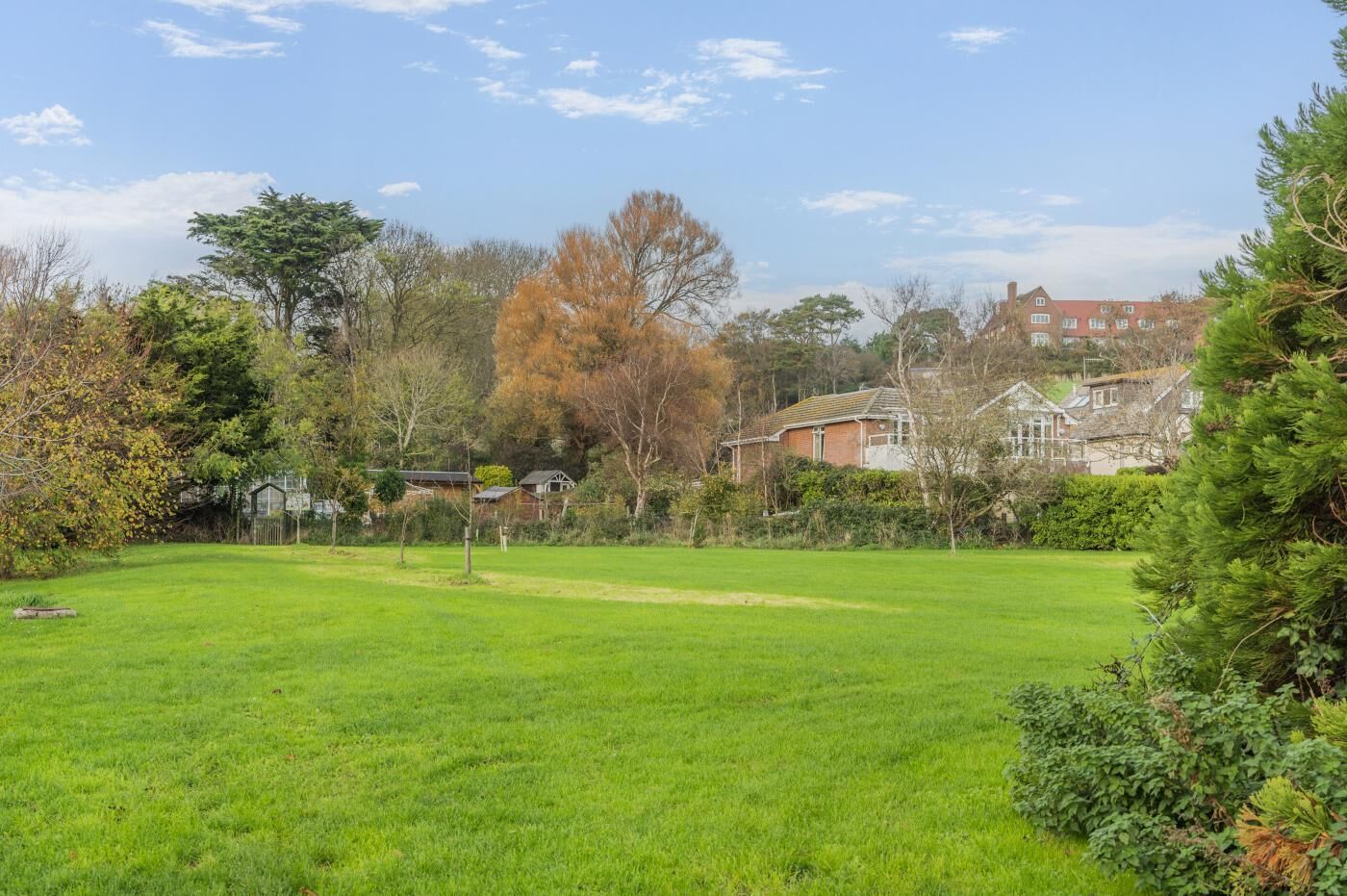 A grassy field with houses in the background.