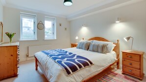 Une chambre à coucher avec un lit, des tables de chevet, une commode et une fenêtre.
