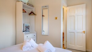 A bedroom with a bed, a dresser, a mirror, and a door. - 3 Bed in Bembridge (oc-s33085) (Bembridge)