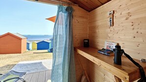 A wooden cabin with a view of the sea, a small table with books and a camera, and a blue curtain. - 3 Bed in Bembridge (oc-s33085) (Bembridge)