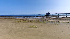 A beach with a pier extending into the water, featuring a building on the pier. - 3 Bed in Bembridge (oc-s33085) (Bembridge)
