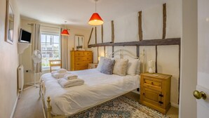 A bedroom with a bed, bedside tables, a dresser, a fan, a TV, and a window with curtains. - 2 Bed in Southwold (oc-hsc) (Southwold)