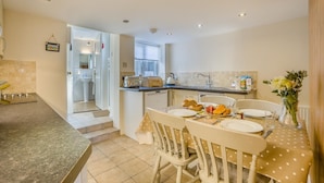 A kitchen with a dining table set for two, a toaster, and a vase with flowers. - 2 Bed in Southwold (oc-hsc) (Southwold)