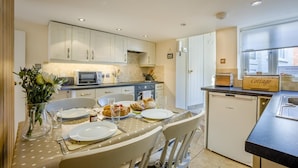 A kitchen with white cabinets, a microwave, a toaster, and a dining table set for four with plates, glasses, and cutlery. - 2 Bed in Southwold (oc-hsc) (Southwold)