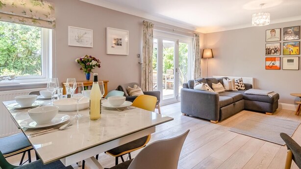 Ein modernes Wohnzimmer mit Essbereich, großen Fenstern und Blick ins Freie.