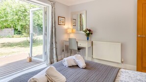 Ein Schlafzimmer mit Bett, Schreibtisch, Stuhl, Heizkörper und einem Fenster mit Vorhängen.