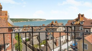 Une ville côtière avec des bâtiments bien visibles, un ciel dégagé et une vue sur la mer.