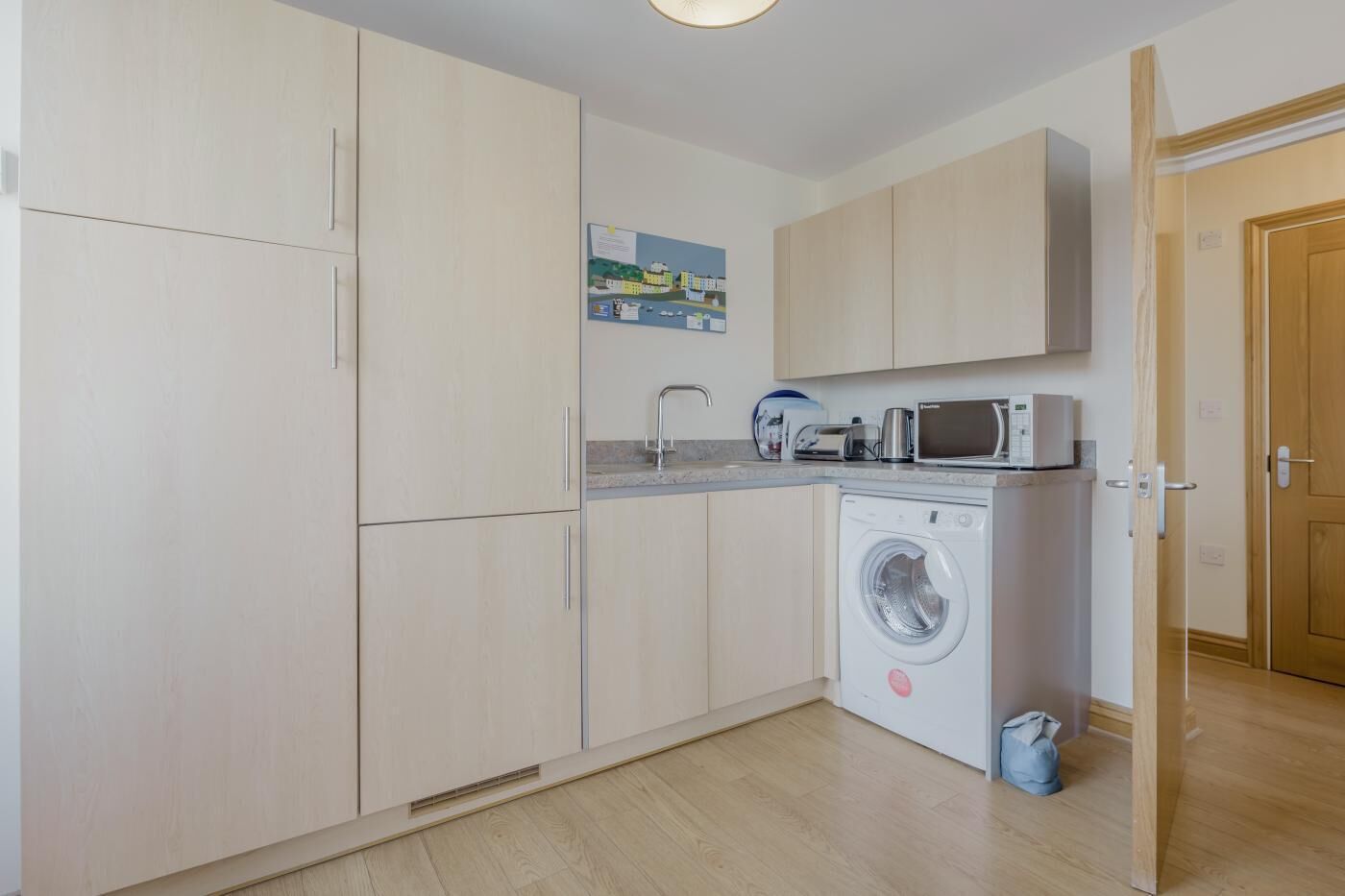 A compact kitchen with a washing machine, a microwave, and a sink.