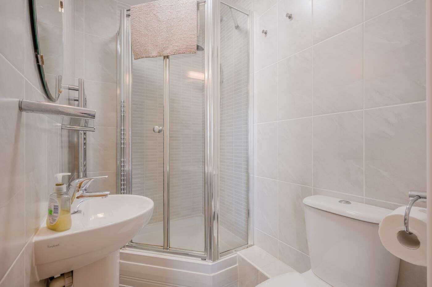 Moderni kylpyhuone, jossa on lasinen suihkuseinä, valkoinen pesuallas ja wc-istuin.