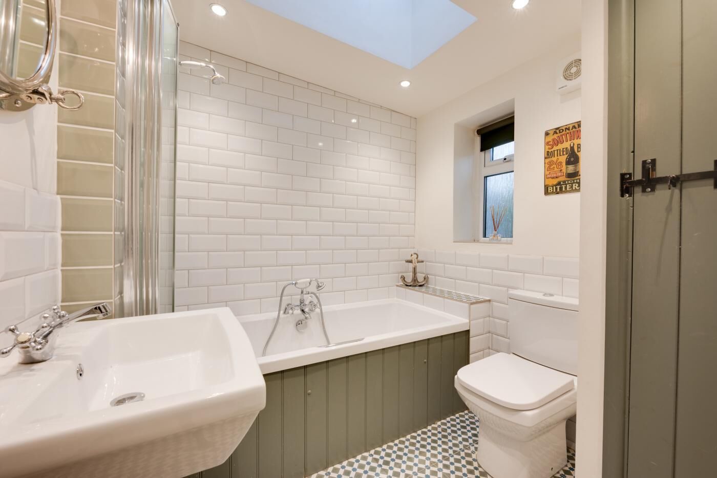 Une salle de bain moderne avec des carreaux blancs, une grande baignoire, un lavabo et des toilettes.