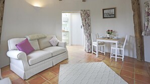 Una sala de estar acogedora con un sofá blanco, una mesa de comedor con sillas y un techo de madera rústica.