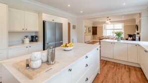 Una cucina moderna con mobili bianchi, un'isola centrale e un'area pranzo con un tavolo e sedie in legno.