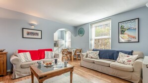 A living room with two sofas, a coffee table, and a dining area with a table and chairs. - 3 Bed in Swanage (oc-wy272) (Swanage)