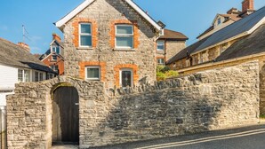 A stone house with a pitched roof, a stone wall, and a wooden gate. - 3 Bed in Swanage (oc-wy272) (Swanage)