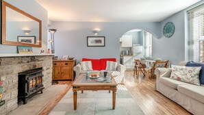 A living room with a fireplace, a sofa, a coffee table, and a dining area. - 3 Bed in Swanage (oc-wy272) (Swanage)
