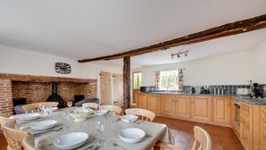 A dining area with a brick fireplace, wooden chairs, and a table set for six. - 4 Bed in Saxmundham (oc-oth) (Dunwich)