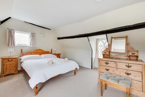 A bedroom with a wooden bed, a dresser, a mirror, and a window with curtains. - 4 Bed in Saxmundham (oc-oth) (Dunwich)