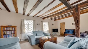 A living room with a wooden ceiling, a bookshelf, a television, and two sofas. - 4 Bed in Saxmundham (oc-oth) (Dunwich)