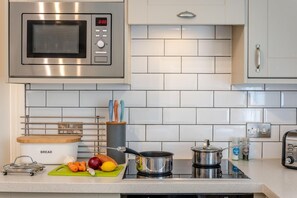 A kitchen with a microwave, bread rack, cutting board with vegetables, a pot, and a toaster. - 2 Bed in Swanage (oc-wy358) (Swanage)