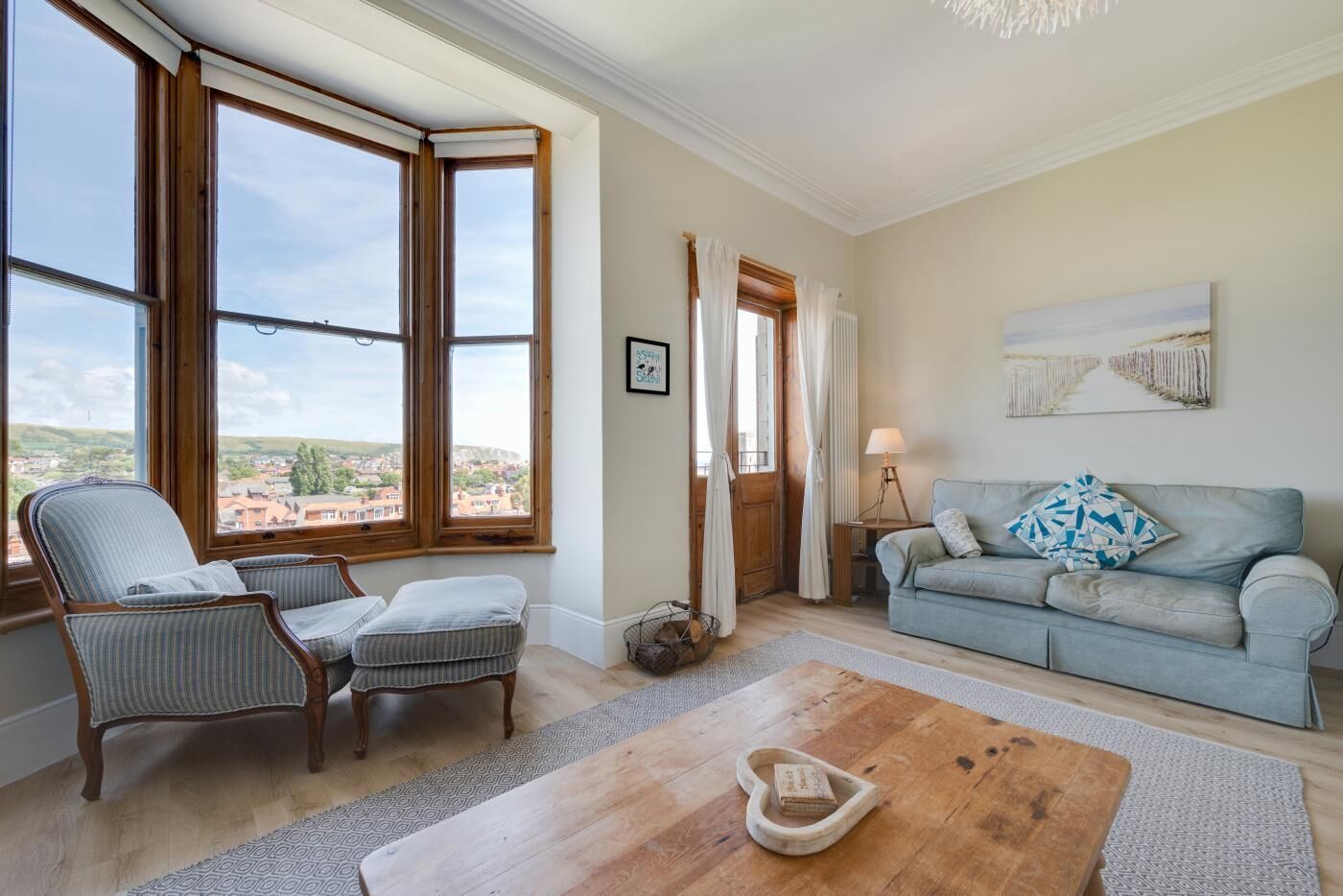 Ein Wohnzimmer mit Blick auf eine Stadt, inklusive Sofa, Sessel und Couchtisch.