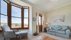 Ein Wohnzimmer mit Blick auf eine Stadt, inklusive Sofa, Sessel und Couchtisch.