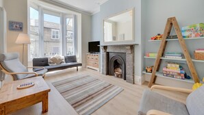 Ein Wohnzimmer mit Kamin, Fernseher und Bücherregal mit Kinderspielzeug.