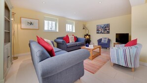 A spacious living room with a fireplace, two sofas, a television, and a striped armchair. - 6 Bed in Knodishall (oc-bil) (Knodishall)