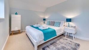 A modern bedroom with a large bed, white dresser, and two bedside tables with lamps. - 6 Bed in Knodishall (oc-bil) (Knodishall)