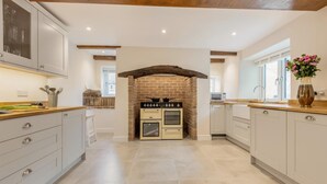A kitchen with white cabinets, a brick archway, and a built-in oven. - 4 Bed in Bere Regis (oc-g33051) (Bere Regis)