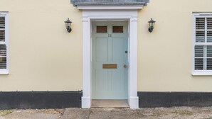 A light blue door with a small window above it, flanked by two wall-mounted lanterns. - 4 Bed in Bere Regis (oc-g33051) (Bere Regis)