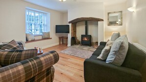 A cozy living room with a fireplace, two sofas, a TV, and a window with blinds. - 4 Bed in Bere Regis (oc-g33051) (Bere Regis)
