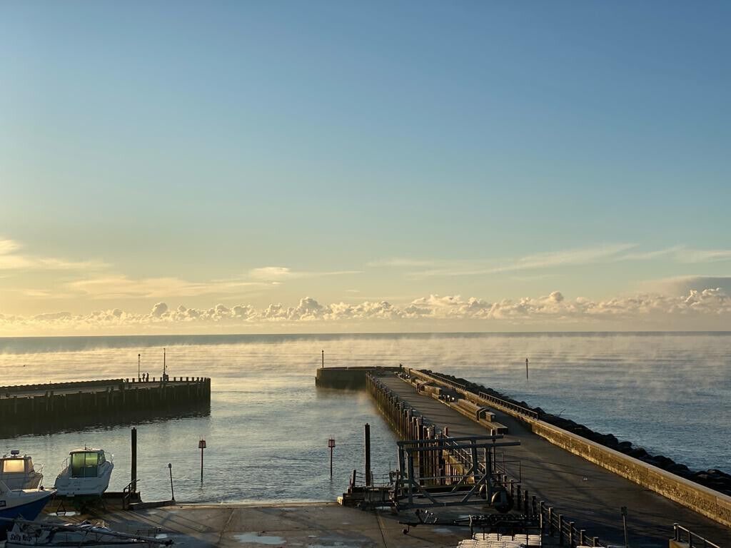 Un muelle se adentra en aguas tranquilas bajo un cielo despejado.