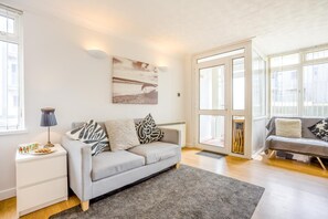 A modern living room with a grey sofa, a coffee table, a lamp, and a painting on the wall.