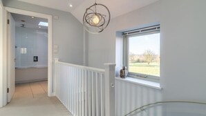 Ein modernes Interieur mit einer Treppe, Blick auf einen Garten durch ein Fenster und einer außergewöhnlichen Pendelleuchte.