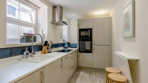 A modern kitchen with a sink, stove, and two stools.