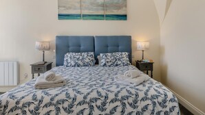 A bedroom with a bed, two nightstands, a headboard, and a wall-mounted painting.