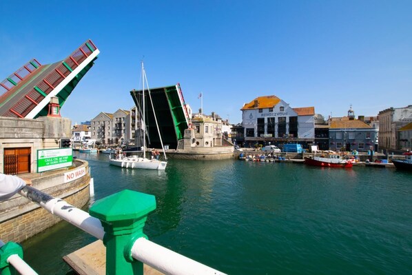 A harbor with boats, a green bridge, and buildings including one with 'RENDEZVOUS' sign.