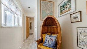 A hallway with a wooden chair, a map, and framed pictures on the walls.