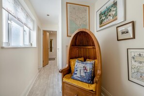 A hallway with a wooden chair, a map, and framed pictures on the walls.