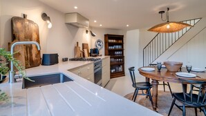 Een moderne keuken met een centraal eiland, een ingebouwde oven en een eethoek met een houten tafel en stoelen.
