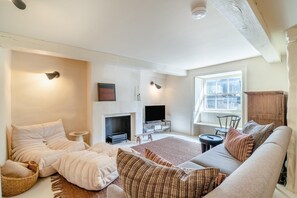 Un salon avec une cheminée, un canapé, une télévision et une fenêtre donnant sur un beau paysage.