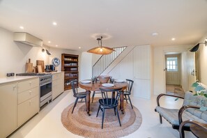 Une cuisine moderne avec un coin repas, comprenant une table ronde, des chaises, une cuisinière et une bibliothèque.