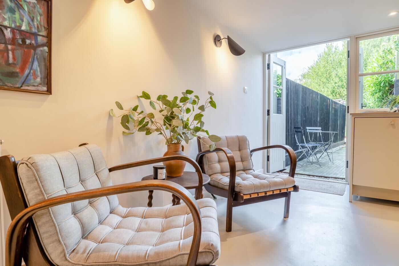 A modern living room with two upholstered chairs, a potted plant, and a large window.