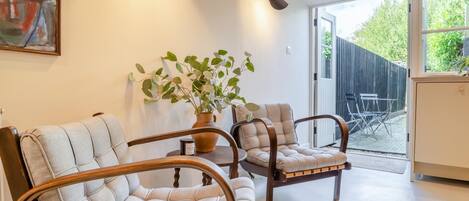 A modern living room with two upholstered chairs, a potted plant, and a large window.