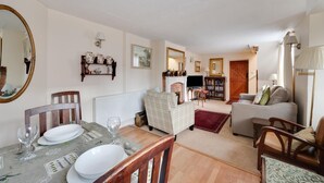 Ein Wohnzimmer mit Kamin, Fernseher, einer Couch und einem Essbereich mit Tisch und Stühlen.