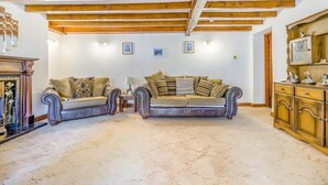 Una sala de estar con dos sofás, una chimenea y techo de madera.