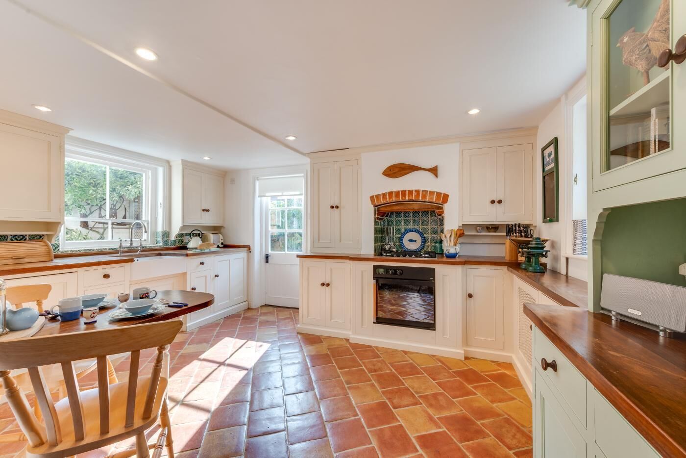 A kitchen with white cabinets, a tiled floor, a wooden chair, and a fish-shaped backsplash.