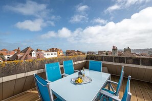 A rooftop terrace with a table and chairs, overlooking a cityscape. - 3 Bed in Swanage (oc-wy269) (Swanage)