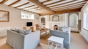 A living room with exposed wooden beams, a fireplace, a television, and two sofas. - 1 Bed in Southwold (oc-rest) (Southwold)
